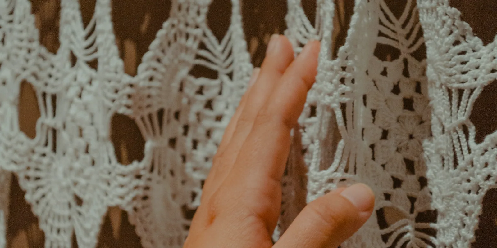 Une main qui effleure un voile de dentelle au crochet