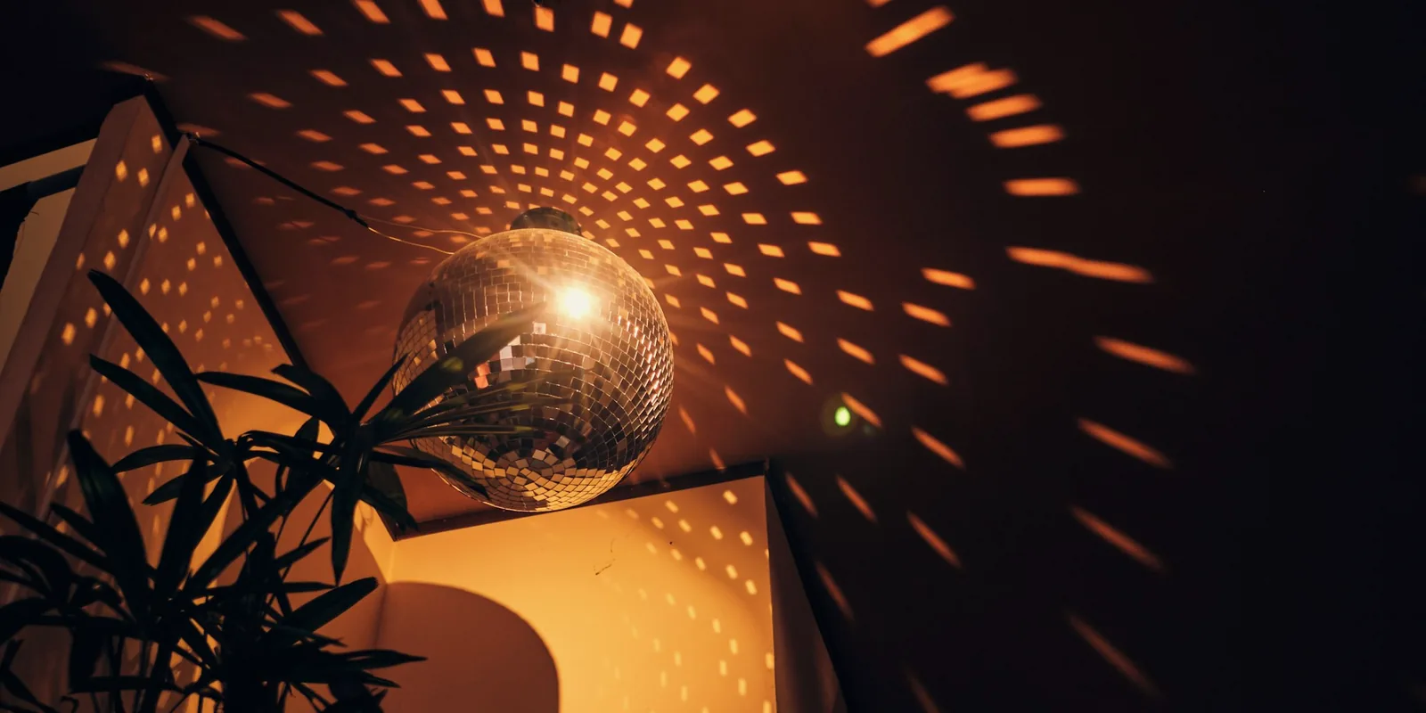 Une boule à facettes qui projette des taches de lumière dorée dans une pièce sombre