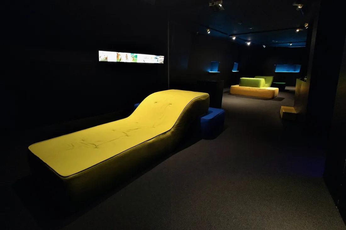 Un salon sombre avec un long canapé jaune et des points de lumière
