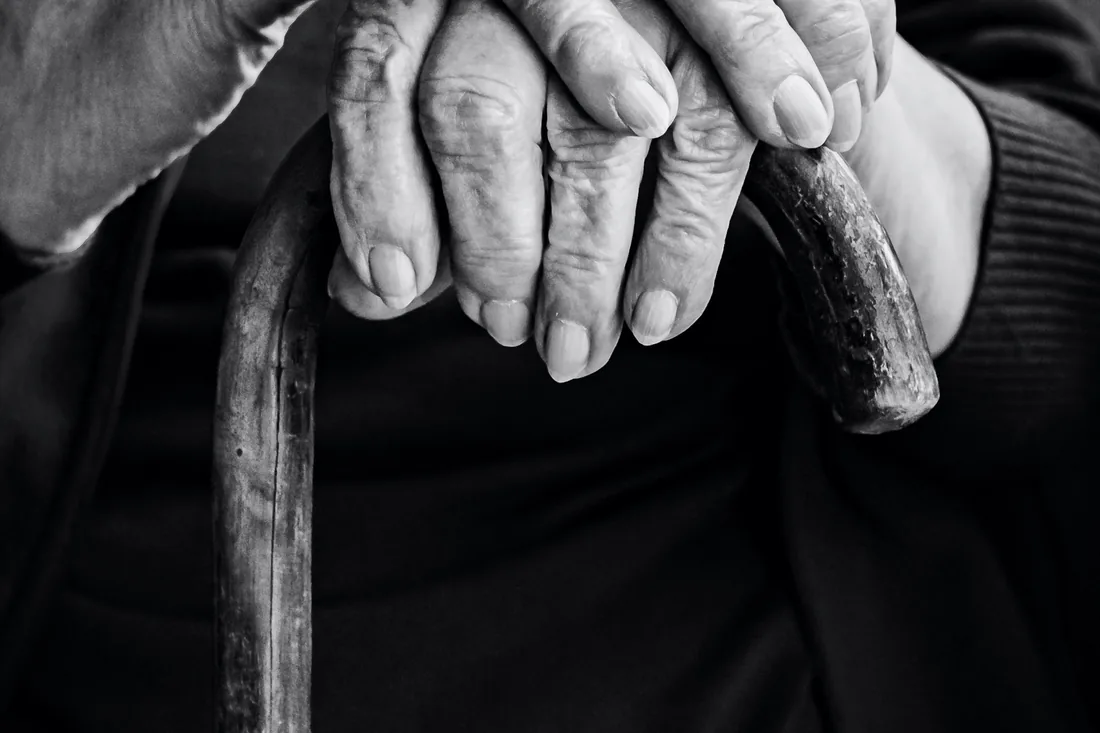 Des mains âgées croisées sur une canne